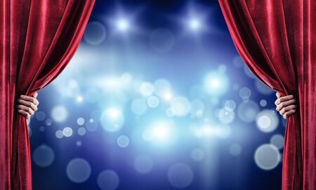 Close up of businessman hand open red velvet curtain of stageの写真素材