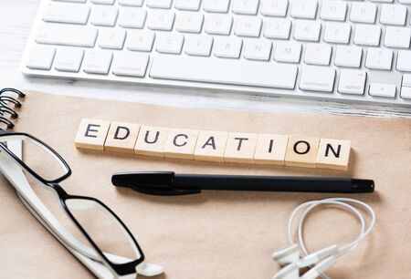 Business education concept with letters on cubes. Still life of office workspace with supplies. Flat lay vintage wooden desk with computer keyboard and spiral notebook. Learning and development.の写真素材