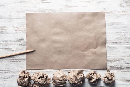 Crumpled brown paper sheet and pencil on wooden tableの写真素材