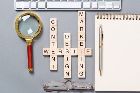 Web marketing concept with words from cubes. Still life of office workplace with crossword. Flat lay...