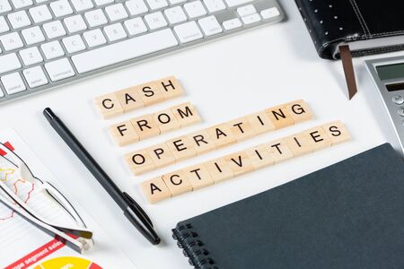 Cash from operating activities concept with letters. Still life of office workplace with supplies....