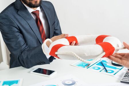 Business persons holding lifebuoy together. Business assistance and professional law consultation. Corporate teamwork and partnership. Insurance services for business. Independent audit and consultingの写真素材