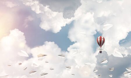 Colorful aerostat flying among paper planes and over the blue cloudy sky. 3D rendering.の写真素材