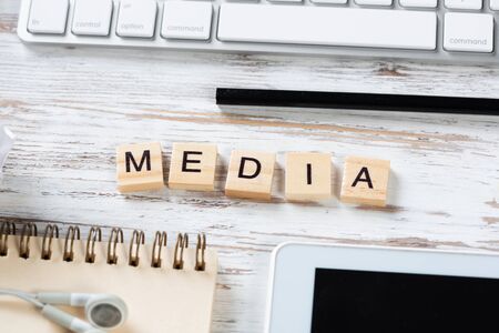 Social media concept with letters on cubes. Flat lay vintage wooden desk with tablet computer, crumpled paper and spiral notebook. Online connection and communication. Still life of blogger workplace.の写真素材