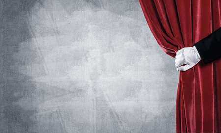 Close up of hand in white glove open red velvet curtainの写真素材