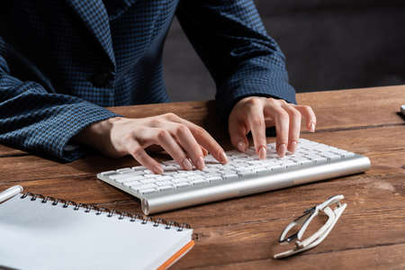 Close up woman hands lying on laptop keyboard. Business lady working with computer at wooden desk. Financial specialist working at workplace in office. Human resources and career development.の写真素材