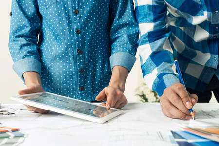 Designers selecting color palette for design project. Decorator using tablet computer for work....