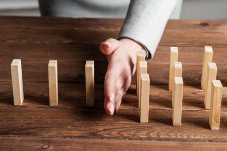 Business woman hand stop domino effect. Operative business solution, strategy and successful intervention. Life insurance company presentation with wooden blocks. Protection from economic crisis.の写真素材