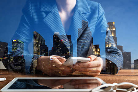 Businesswoman using mobile phone at desk. Close up woman hands and tablet computer. Mobile communication concept with chatting woman. Digital technology in strategy planning and company managementの写真素材