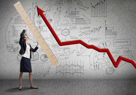 Woman holding big ruler on wall background. Business development to success. Businesswoman measuring growing arrow chart with big ruler. Creative motivation and company analytics presentation.の写真素材