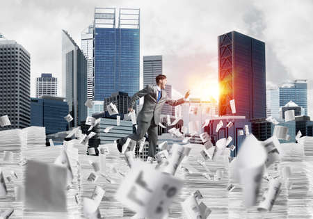 Businessman in suit running with phone in hand among flying papers with sunlight and cityscape on background. Mixed media.の写真素材