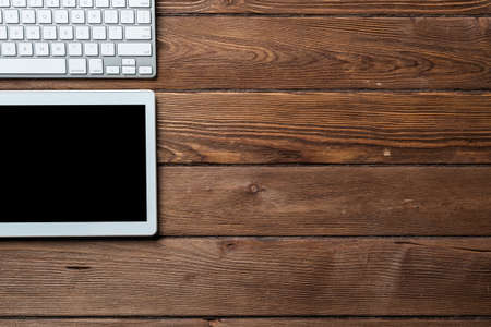 Top view of modern working place. Tablet computer and computer keyboard on vintage wooden surface. Education, creativity and innovation concept with copy space. Digital technology in modern business.の写真素材
