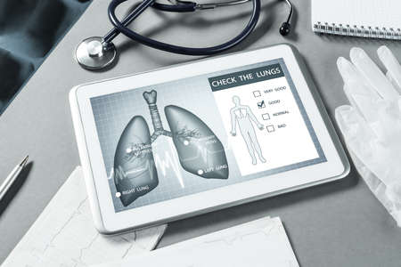White tablet pc and doctor tools on gray surfaceの写真素材