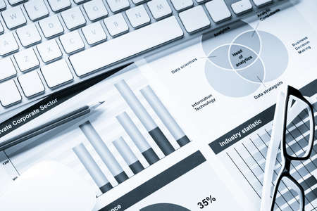 Business workplace with keyboard mouse and papers with graphs and diagrams