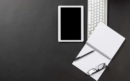 Top view of modern workplace with tablet computer. Flat lay black surface with keyboard and open...