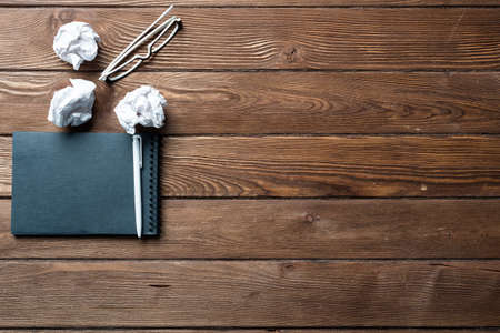 Top view of well organized home office workplace. Black spiral notepad, crumpled paper and glasses...
