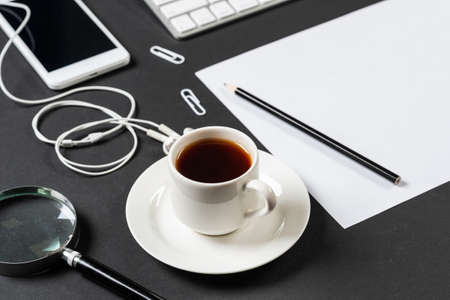 Top view of modern workplace with blank paper sheet. Flat lay black surface with smartphone, notepad...