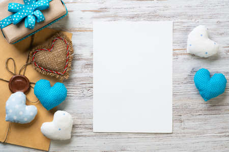 Flat lay cute composition with handmade fabric heart. White paper and retro mail envelope on wooden table. Happy birthday or anniversary congratulation. Romantic message template with copy spaceの写真素材