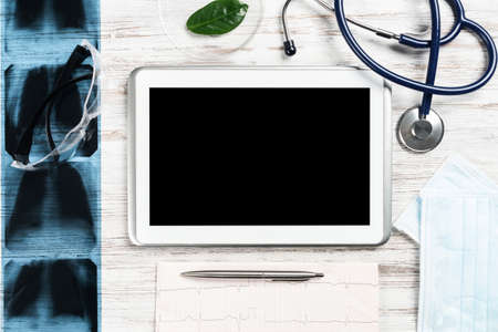 Mock up of doctors desktop with medical supplies. Tablet computer, x-ray image, stethoscope and...