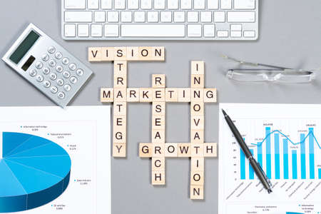 Business motivation concept with words from cubes. Still life of office workplace with crossword. Flat lay grey surface with computer keyboard and calculator. Strategy planning and business analyticsの写真素材