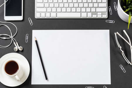 Top view of modern workplace with blank paper sheet. Flat lay black surface with smartphone, notepad...