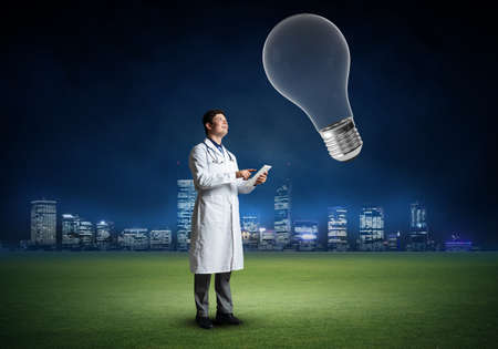 The doctor stands in front of the light bulb symbol. innovation in medicineの写真素材