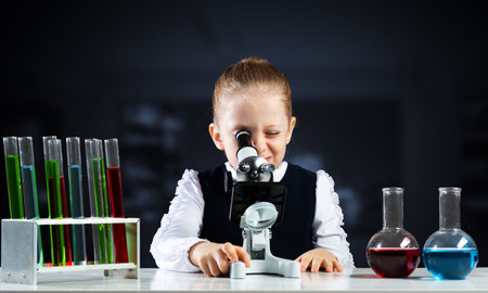 Little scientist looking through microscope in classroom. Research and education in modern school....