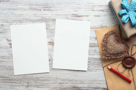 Flat lay composition with handmade fabric heart and gift box. Blank sheet of white paper on wooden...