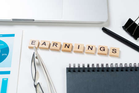 Earnings management concept with letters on wooden cubes. Still life of office workplace with...