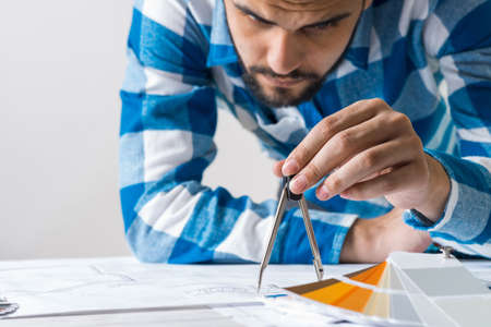 Man measuring with compass divider on construction blueprint. Architect workplace with technical...
