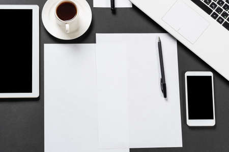 Top view of designer workplace with modern digital devices. Flat lay stylish design with black surface and copy space. Digital technology and mobile lifestyle. Laptop, tablet computer and smartphone.の写真素材