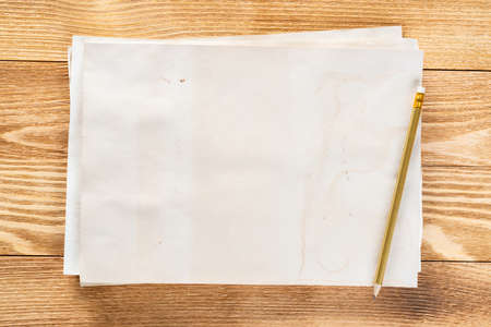 Artist workplace with sheet of paper and pencil lying on wooden desk. Rectangular white paper stack with blank copy space. Textured natural wooden background. Art school template for advertisingの写真素材