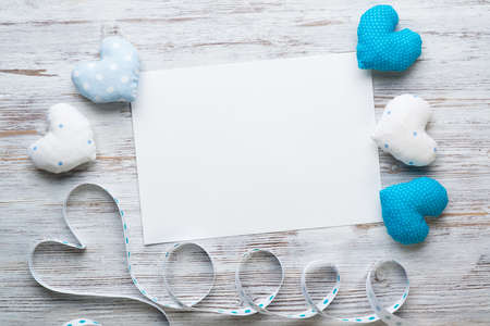 Flat lay composition with blue and white love hearts. Blank sheet of white paper on vintage wooden table. Declaration of love letter. Saint Valentines day congratulation. Romantic event invitation.の写真素材