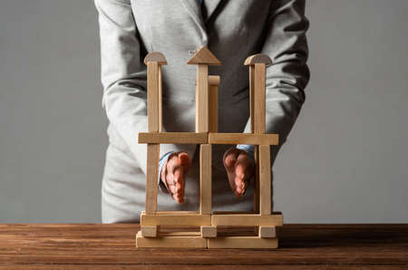 Business woman building construction on table from wooden blocks. Architecture engineering and...