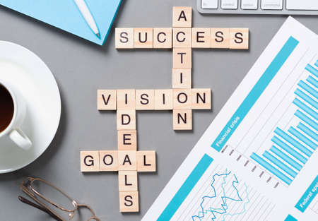 Business motivation concept with words from cubes. Still life of office workplace with crossword....