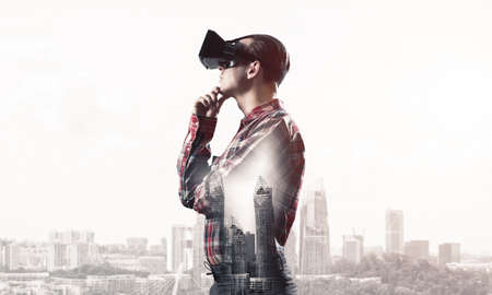Young man with virtual reality headset or 3d glasses over cityscape backgroundの写真素材