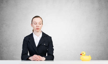 businesswoman at the table with a yellow toy duckの写真素材