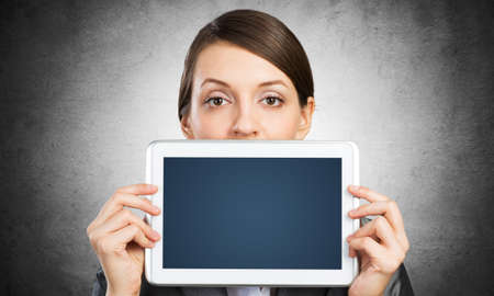 Businesswoman holding tablet computer with blank screen. Beautiful woman in business suit show...