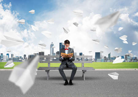 young businessman with a book. flying around paper plane in chaosの写真素材