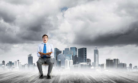 young businessman with book on office chairの写真素材