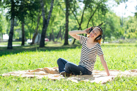 Young attractive woman listens to music in the park. Enjoying music in the parkの写真素材