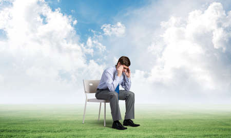 Businessman is sitting on an office chair with his head in his hands. Business stress and problemsの写真素材