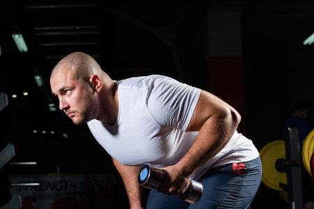 Male bodybuilder engaged with dumbbells in the gym. Healthy lifestyle