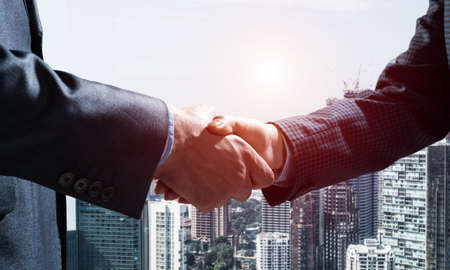 Close-up of the handshake of businessmen. Against the backdrop of the cityscape