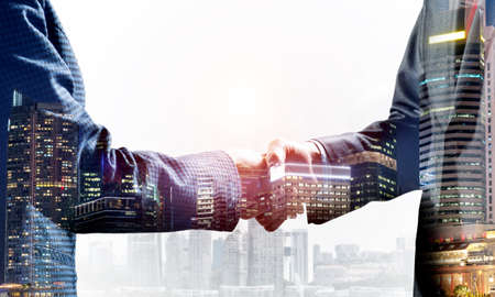 Close-up of the handshake of businessmen. Against the backdrop of the cityscapeの写真素材