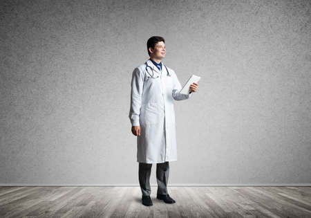 The Doctor holds a computer tablet and looks in front of him.の写真素材