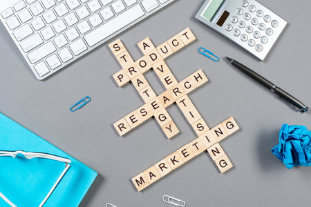 Web marketing concept with words from cubes. Still life of office workplace with crossword. Flat lay grey surface with computer keyboard and notebook. Sales strategy planning and product promotion.の写真素材