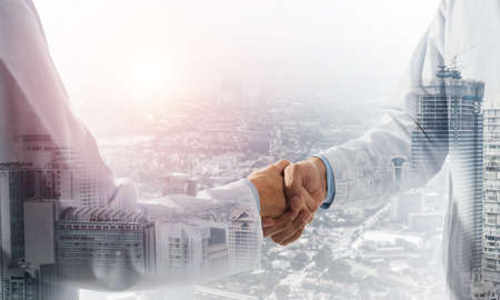 Close-up of the handshake between the two medics. Against the backdrop of the cityscapeの写真素材