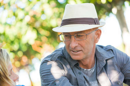 Winegrowers relaxing in garden at sunny day. Father and son gardeners speaking and looking each...