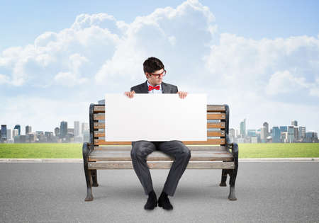 Young businessman holds a large white banner. sits on the benchの写真素材